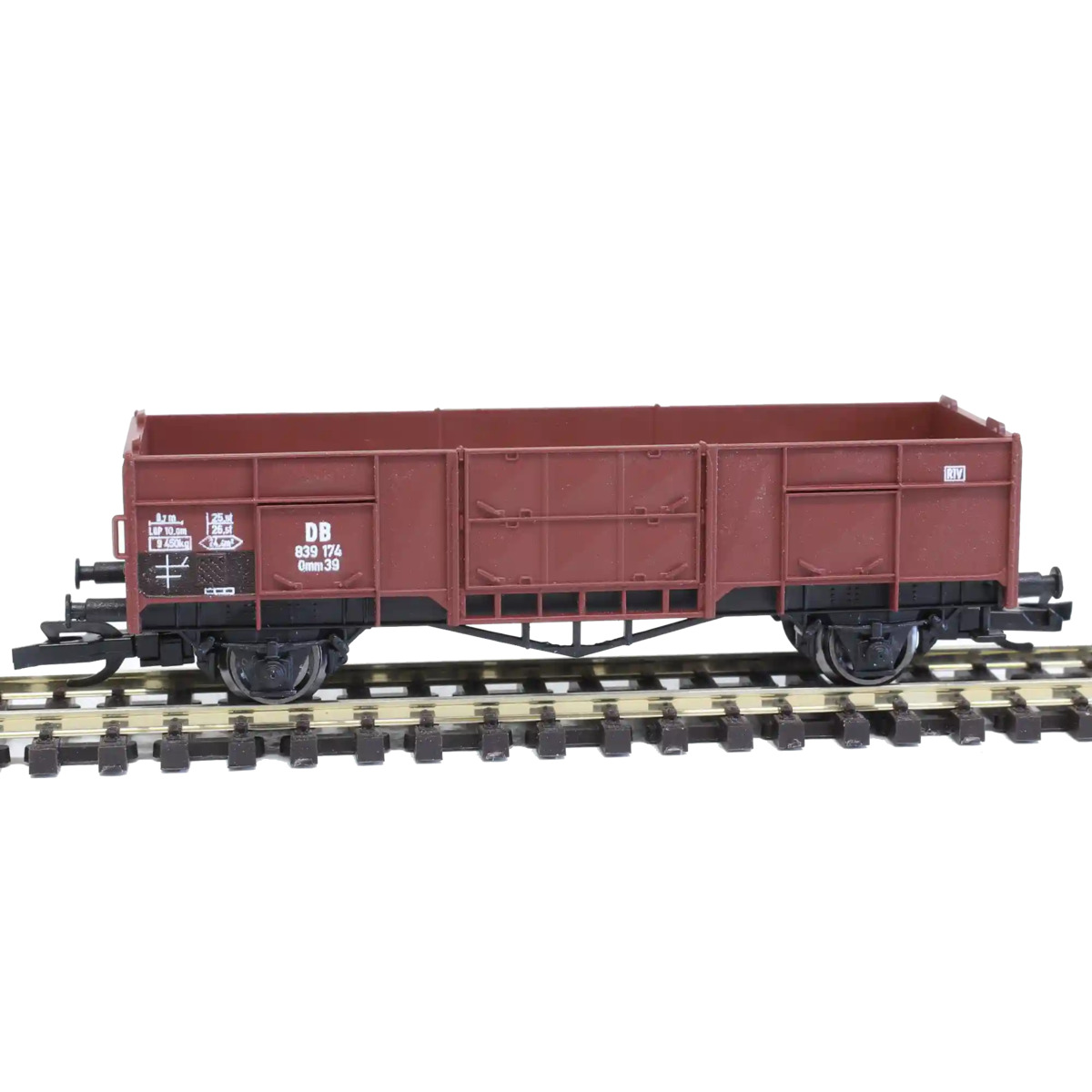 TT scale open freight wagon in DB livery standing on a small model railway siding near an industrial loading area, loose aggregate cargo, realistic miniature scenery, soft daylight, detailed macro photography