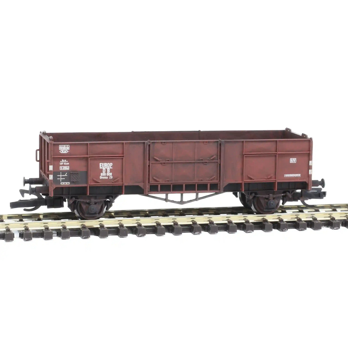 Patinated TT scale open freight wagon on a realistic mid-20th-century European model railway, industrial loading yard with gravel piles, soft natural daylight, detailed miniature scenery